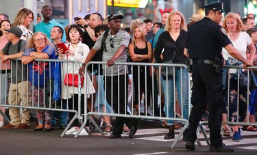 Spectators passing through Times Square stop at a police barricade used to cordon off the scene of a deadly car crash Thursday, May 18, 2017, in New York. A 26 year-old U.S. Navy veteran steered his car onto a sidewalk running through the heart of Times Square and mowed down pedestrians for three blocks Thursday. The driver was subdued by police and bystanders at the site. (AP Photo/Kathy Willens)