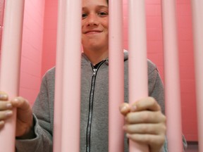 Morris Dubé of Mississauga poses behind cell bars in one of the pink-painted cells at the Stirling-Rawdon Police Service headquarters on Saturday May 20, 2017 in Stirling, Ont.  Dubé was one of several taking a tour of the building as part of an SRPS open house. Tim Miller/Belleville Intelligencer/Postmedia Network