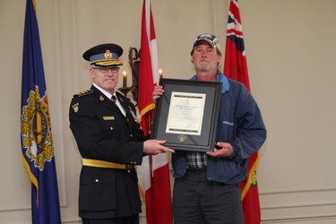 Ross Guy holds receives the award from OPP Commissioner Vince Hawkes. (Tracy McLaughlin/Toronto Sun/Postmedia Network)
