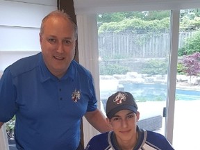 Sudbury Wolves 2017 draft pick Anthony Tabak prepares to sign on the dotted line while Wolves VP and GM Rob Papineau looks on. Supplied photol