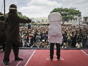 Shariah law official whips one of two men convicted of gay sex during a public caning outside a mosque in Banda Aceh, Aceh province, Indonesia, on Tuesday, May 23, 2017. (Heri Juanda/AP Photo)