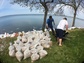 Big Sandy Bay Management Area workers Keith Jeffrey, left, and Graeme Tobias unload sandbags for a resident of Easy Lane on Wolfe Island on Wednesday. (Elliot Ferguson/The Whig-Standard)