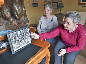 Cecile Dionne, right, places a photo of herself and her sisters when they were children on a desk at the St. Bruno, Que., home of her sister Annette. John Kenney / Postmedia Network