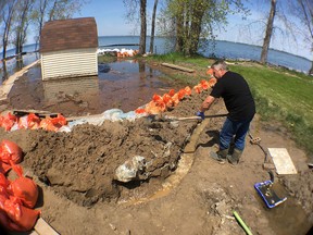 Gordon Cobain repairs a sandbag berm that is keeping floodwaters from his home on Easy Lane on Wolfe Island, Ont. on Wednesday, May 24, 2017. 
Elliot Ferguson/The Whig-Standard/Postmedia Network