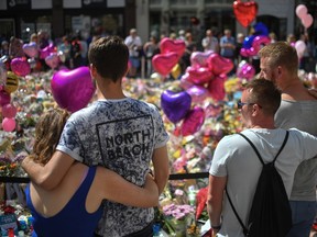 Couples comfort one another as flowers and balloons are left in Saint Ann's Square in tribute to those killed in an explosion at the Manchester Arena earlier this week on May 26, 2017 in Manchester, England. (Anthony Devlin/Getty Images)