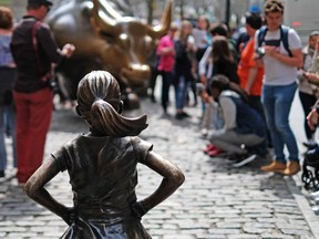 The "Fearless Girl" (front) statue stands facing the "Charging Bull" as tourists take pictures in New York on April 12, 2017. (JEWEL SAMAD/AFP/Getty Images)