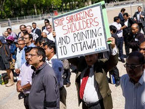 People hold signs during a rally for unemployed energy workers at the Alberta Legislature Building in Edmonton on Tuesday, May 30, 2017. Codie McLachlan/Postmedia