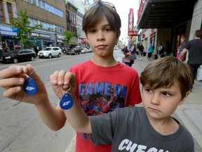 Xander Logan, 9, and his brother Micah, 5, of London show the key fobs they use to ride free on LTC buses Wednesday. (MORRIS LAMONT, The London Free Press)