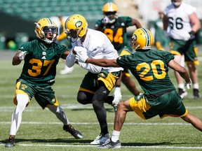 Adarius Bowman, centre, breaks through Kenny Ladler, left, and Johnny Adams, right, during Edmonton Eskimos training camp at Commonwealth Stadium in Edmonton on Monday, May 29, 2017.