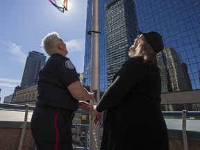 Toronto Police Const. Danielle Bottineau (left) and Christine Newman, co-chair, Toronto police LGBTG community consultative committee, raise the Pride flag at Toronto Police Service headquarters in Toronto, on Thursday, June 1, 2017. (ERNEST DOROSZUK/TORONTO SUN)