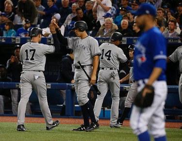 Toronto Blue Jays Marco Estrada P (25-right) watches as New York Yankees Matt Holliday DH (17) high fives teammate Aaron Judge RF (99) after they scored three runs in the first inning  in Toronto, Ont. on Thursday June 1, 2017. Jack Boland/Toronto Sun/Postmedia Network