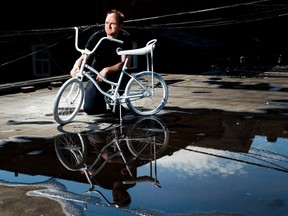 Geoffrey Bercarich poses for a photograph with the ghost bike he painted on roof of his apartment for a five year-old boy who died in a cycling accident in Toronto on Wednesday, May 31, 2017. Bercarich creates ghost bikes for victims who die in bicycles accidents on the street of Toronto. (Nathan Denette/THE CANADIAN PRESS)