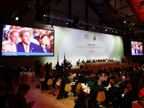 US Secretary of State John Kerry appears on television screens during the final conference at the COP21, the United Nations conference on climate change, in Le Bourget, north of Paris, Saturday, Dec.12, 2015. Governments have adopted a global agreement that for the first time asks all countries to reduce or rein in their greenhouse gas emissions. (AP Photo/Francois Mori)