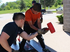 Lambton College student Sam Poier helps Bennett Schleihauf with his first sledge hammer swing. The skill is part of what's learned in the college's firefighting program. (NEIL BOWEN/Sarnia Observer)