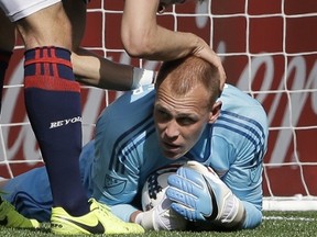 Revolution goalkeeper Cody Cropper receives support from teammate defender Antonio Delamea Mlinar after making a save. New England is 8-0-2 in its past 10 games at home.  (AP Photo/Steven Senne)