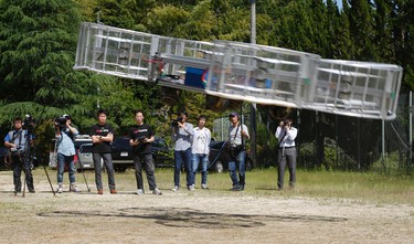 Tsubasa Nakamura, project leader of Cartivator, third from left, watches the flight of the test model of the flying car on a former school ground in Toyota, central Japan, Saturday, June 3, 2017 as another member, fourth from left, operates the remote control. (AP Photo/Koji Ueda)