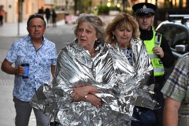 A police officer escorts members of the public, wrapped in foil blankets, towards The Shard in London on June 4, 2017, following a terror attack. (CHRIS J. RATCLIFFE/AFP/Getty Images)