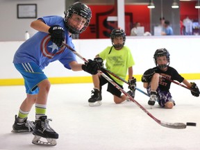 Evan Guay and Braydon Barnes watch classmate Liam Duench, 8, fire a shot during a drill set up by former London Knight Brett Welychka at the Snipe Academy on Friday. (MIKE HENSEN, The London Free Press)