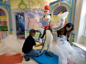 In this May 4, 2017, photo John Simpson, left, project director of exhibitions for The Amazing World of Dr. Seuss Museum, and his wife Kay Simpson, right, president of Springfield Museums, unwrap a statue of the "Cat in the Hat," at the museum, in Springfield, Mass. The museum devoted to Dr. Seuss, which opened on June 3 in his hometown, features interactive exhibits, a collection of personal belongings and explains how the childhood experiences of the man, whose real name is Theodor Geisel, shaped his work. (AP Photo/Steven Senne)