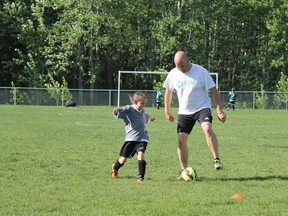 Photo by Jesse Cole Reporter/Examiner
Coach Dean Guskarth, helps a player with soccer drills during a practice on May 30.