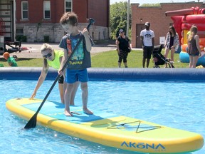 Cooper Rankin, 6, of Wallaceburg, Ont., tries out paddle boarding with the help of Kasey Martin, a counsellor at Chatham-Kent's Special Populations summer camp during the Chatham-Kent Youth Festival, held at Tecumseh Park in Chatham.