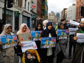 Chairman of the London Fatwa Council, Mohammad Yazdani Raza, right, holds a sign as he marches with others near Borough Market in London, Sunday, June 4, 2017. Police specialists collected evidence in the heart of London after a series of attacks described as terrorism killed several people and injured more than 40 others. (AP Photo/Frank Augstein)