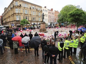 People observing a minute's silence in St Ann's Square, Manchester, England, in honour of the London Bridge terror attack victims, Tuesday June 6, 2017. A new search was underway Tuesday in a neighborhood near the home of two of the London Bridge attackers, hours after police said they had freed everyone detained in the wake of the rampage that left several dead and dozens wounded. (Peter Byrne/PA via AP)