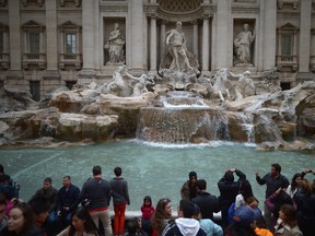 In this file photo, tourists visit the Trevi Fountain on March 25, 2013 in Rome, Italy. (Photo by Jeff J Mitchell/Getty Images)
