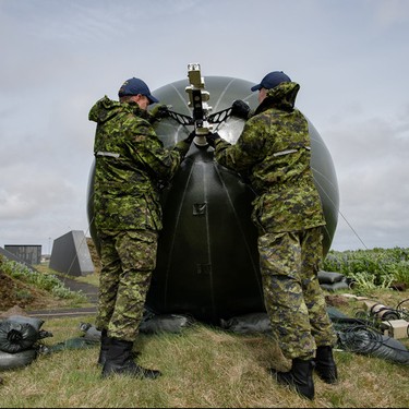 Warrant Officer Craig Adamson (left) and Corporal Zachary Thomson (right), members of 8 Air Communication and Control Squadron deployed with Air Task Force-Iceland, adjust a satellite antenna against a strong wind at Keflavik Air Base on May 29, 2017, during Operation REASSURANCE. 

Photo: Corporal Gary Calvé. Imagery Technician ATF-ICELAND