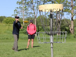 Sandra Hendel watches as her brother, Martin, throws a disc towards a disc golf basket. Both players will be traveling later this month to Augusta, Ga., to participate in this year’s disc golf world championship. (JONATHAN JUHA/TIMES-JOURNAL/POSTMEDIA NETWORK)