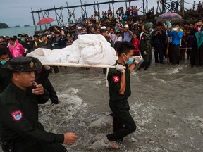 Myanmar military members carry a dead body at Sanhlan village on June 8, 2017. Hundreds of people gathered solemnly on a beach in southern Myanmar awaiting news of their loved ones as rescuers worked to pull bodies from the Andaman Sea after a military plane crashed with more than 120 people on board. / AFP PHOTO / Ye Aung ThuYE AUNG THU/AFP/Getty Images