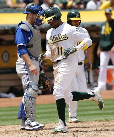 Oakland Athletics' Rajai Davis (11) scores in front of Toronto Blue Jays catcher Russell Martin during the fifth inning of a baseball game in Oakland, Calif., Wednesday, June 7, 2017. (AP Photo/Jeff Chiu)