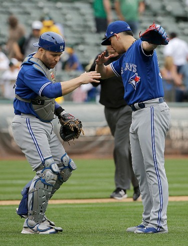 Toronto Blue Jays catcher Russell Martin, left, and pitcher Roberto Osuna celebrate after the final out of the team's baseball game against the Oakland Athletics in Oakland, Calif., Wednesday, June 7, 2017. The Blue Jays won 7-5 in 10wbb innings. (AP Photo/Jeff Chiu)