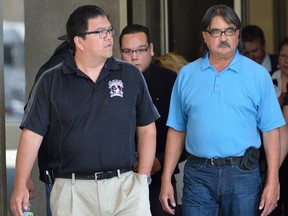 Scott Altiman, centre, hides behind a group of supporters as he leaves the London courthouse after pleading guilty to two counts of impaired driving causing death and six other charges Thursday. (MORRIS LAMONT, The London Free Press)