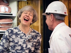 Prime Minister Theresa May laughs as she visits Smithfield Market in London, Wednesday June 7, 2017, on the final day of campaigning ahead of the general election on Thursday. (Stefan Rousseau/PA via AP)