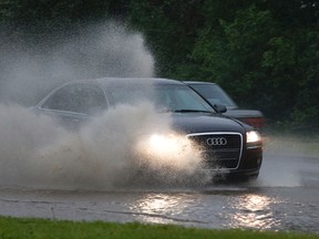 A car drives through a flooded portion of River Valley Road during heavy rains in Edmonton, Alta., on Monday, July 15, 2013.