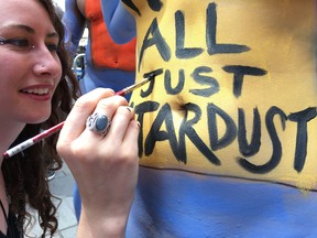 Artist Caren Charles paints the message ’We’re All Just Stardust’ around the bellybutton of model Brooke Champlain at the Body Notes nude body painting event in Times Square on Friday, June 9, 2017. (AP Photo/Dino Hazell)