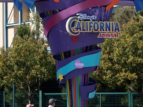 Pedestrians walk near the entrance to Disneyland and California Adventure theme parks on February 19, 2009 in Anaheim, Calif. (Photo by David McNew/Getty Images)