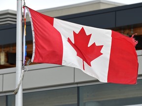 Still visible, a piece of the torn pride flag (L) next to the Canadian flag outside the Lilian Osborne School was cut down Saturday in Edmonton, June 11, 2017. Ed Kaiser/Postmedia