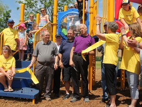 Shawn Pearce (blue shirt), president of Inverary Youth Activities Inc., South Frontenac Mayor Ron Vandewal (purple shirt), Judy Borovski, chairperson of the Playground Committee and many volunteers celebrate the opening of a brand-new play structure at Ken Garrett Park in Inverary on Saturday. (Steph Crosier/The Whig-Standard)