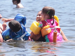 Clinton and Andrea Barry, along with their children Elizabeth and Jacob, cool off in Ramsey Lake at the main beach in Bell Park on Sunday. The beach was a busy place as temperatures hovered around the 30 C mark. (Gino Donato/Sudbury Star)