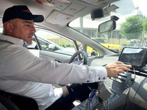 George Chamoun, chair of the Capital Taxi unit of the taxi union, shows off the driver tablet that displays the information of customers who order rides through a new app. Jon Willing, Postmedia.