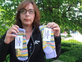 Dimitra Bolton of London holds up women's and men's socks that she is selling in support of the Canadian Cancer Society. The stripes represent different forms of cancer such as breast, lung, colon, ovarian and children's. For each pair sold, $2 will go towards cancer research. (Shalu Mehta, The London Free Press)