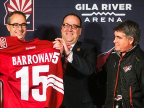 Arizona Coyotes owner Andrew Barroway, left, receives jersey from co-owner, president and CEO Anthony LeBlanc, and Coach Dave Tippett, right, during an NHL hockey news conference, Friday, Jan. 2, 2015, in Glendale, Ariz. (AP Photo/The Arizona Republic, Tom Tingle)