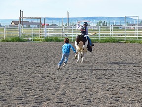 A young bull rider and his bullfighter counterpart master their skills in the rodeo arena in Brocket during the Piikani youth program.