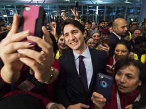 Prime Minister Justin Trudeau poses for selfies with workers before he greets refugees from Syria at Pearson International airport on Dec. 10, 2015. (THE CANADIAN PRESS)