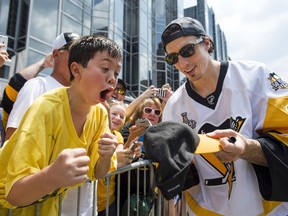 Pittsburgh Penguins' Marc-Andre Fleury signs a hat for a young fan during the team's Stanley Cup NHL hockey victory parade on June 14, 2017, in Pittsburgh. (Steph Chambers/Pittsburgh Post-Gazette via AP)
