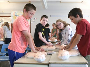 Grade 6 students Brady Fedat-Tellier, left, Denis Anderson, Anna Shaver and Zach Johnson learn how to perform hands-only CPR at Ecole St-Denis in Sudbury, Ont. on Wednesday June 14, 2017. John Lappa/Sudbury Star/Postmedia Network