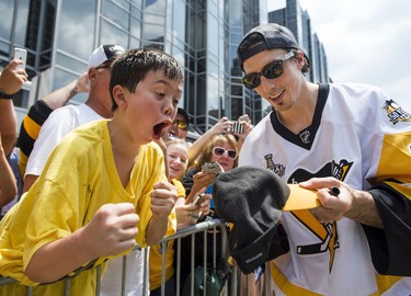 Pittsburgh Penguins' Marc-Andre Fleury signs a hat for a young fan  during the team's Stanley Cup NHL hockey victory parade on Wednesday, June 14, 2017, in Pittsburgh.(Steph Chambers/Pittsburgh Post-Gazette via AP)