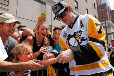 Pittsburgh Penguins' Evgeni Malkin (71) autographs a young fan's arm along the parade route during the team's Stanley Cup NHL hockey victory parade on Wednesday, June 14, 2017, in Pittsburgh. (AP Photo/Gene J. Puskar)